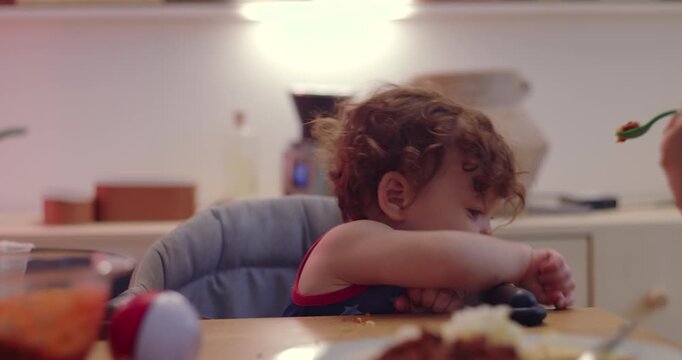 Toddler briefly turns away from mother&rsquo;s spoon at home dining table, then accepts food after she tries again, showing patience, trust and responsive mealtime care