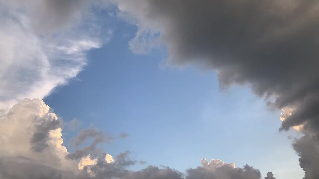 Dramatic Storm Clouds Creating a Natural Frame Around a Clear Patch of Blue Sky During an Afternoon Atmosphere