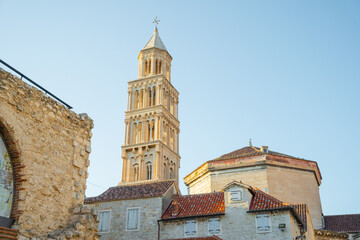 Fototapeta premium A low angle view showing the tall Romanesque bell tower of Saint Domnius Cathedral and traditional red roofs in the historic old town of Split, Croatia.