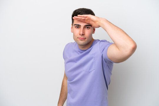 Young caucasian man isolated on white background looking far away with hand to look something