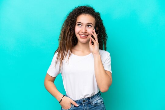 Young Arab woman isolated on blue background keeping a conversation with the mobile phone with someone