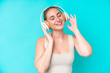 Fototapeta premium Young caucasian woman isolated on blue background listening music and singing
