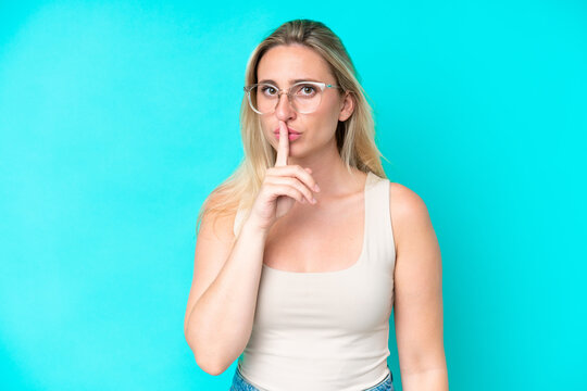 Young caucasian woman isolated on blue background With glasses and doing silence gesture