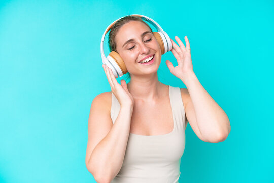 Young caucasian woman isolated on blue background listening music and singing