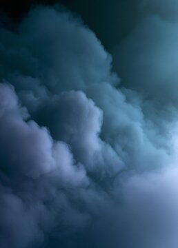 Close-up of a cloudy sky. the clouds are white and fluffy, and they appear to be floating in the air. the background is dark, and the clouds are a lighter shade of blue.