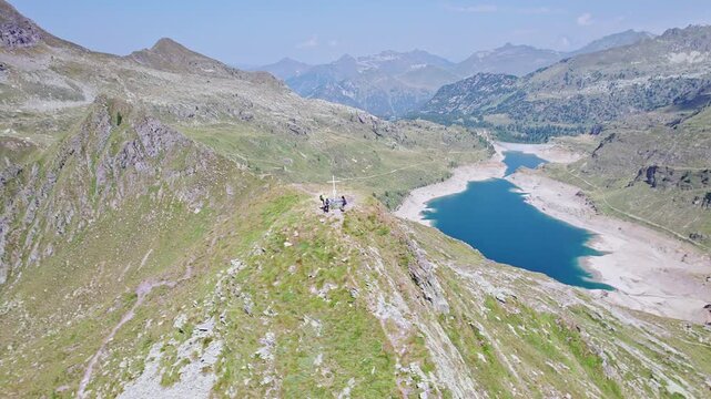 Hikers on top of mountain peak with Twin lakes on background, Orobie mountains, Lombardy landscape
