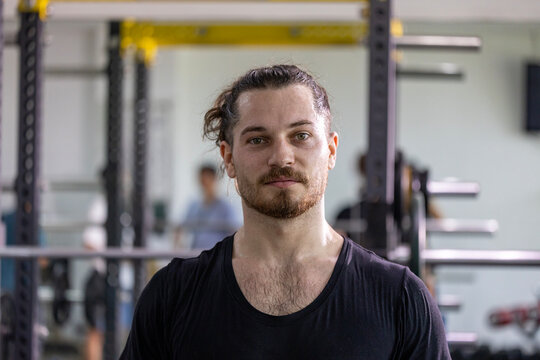 Portrait of caucasian muscular man with perfect abs and bicep muscle inside gym with dark background for exercise and workout in high contrast low key lighting studio