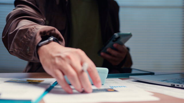 Person manages budget calculating funds checking credit card payments workspace reviewing digital documents analyzing commercial finance transactions accounting corporate tasks monitoring monetary.