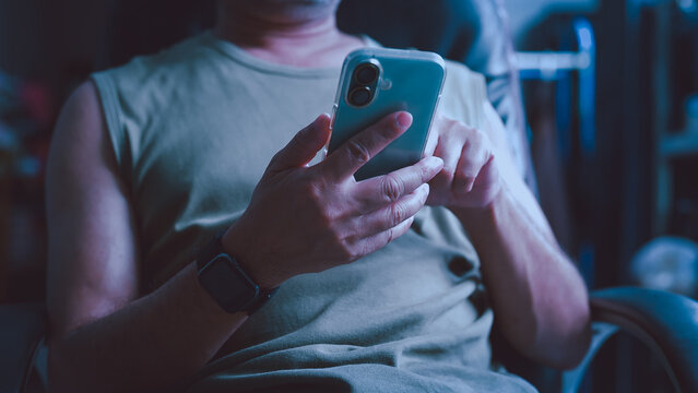 Man holding smartphone typing message indoor room sitting chair wearing casual clothing smartwatch checking mobile application digital screen online communication connectivity network social media.