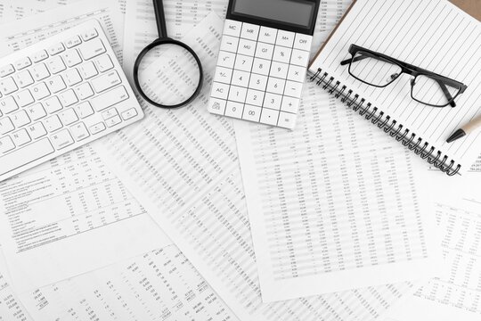 Accounting workspace with calculator magnifying glass eyeglasses and financial data reports, calculator