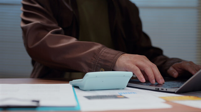 Professional operating keyboard calculator desk reviewing financial report documents accounting data business corporate enterprise workplace management budget planning strategy tax calculation.