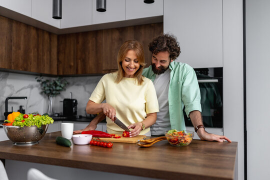 Couple prepares fresh vegetables together in modern kitchen with bright lighting
