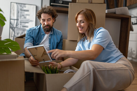 Couple unpacks boxes and looks at a tablet in their new living space