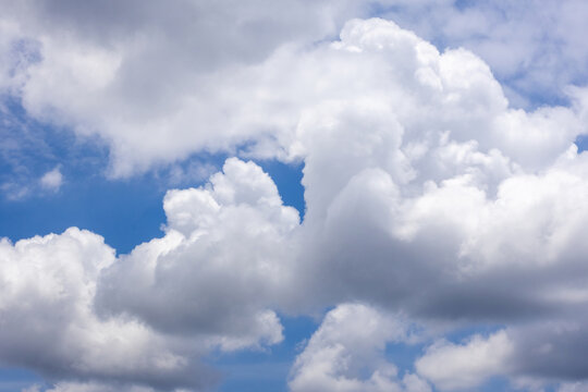 Scenic view of fluffy white cumulus clouds floating in bright blue sky on sunny day. Beautiful atmospheric sky background in summer season outdoors.