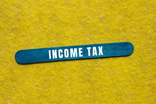 Income tax text on a blue wooden stick over a yellow background, symbolizing financial obligations and annual returns