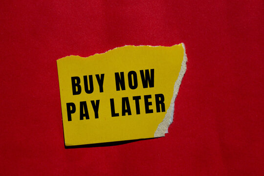 Yellow torn paper with buy now pay later message against a vibrant red background, representing consumer finance and credit