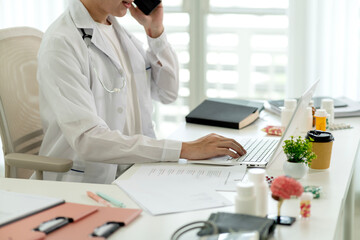 Fototapeta premium Professional Doctor Consulting Patient via Telemedicine Video Call Using Laptop at Modern Clinic Office