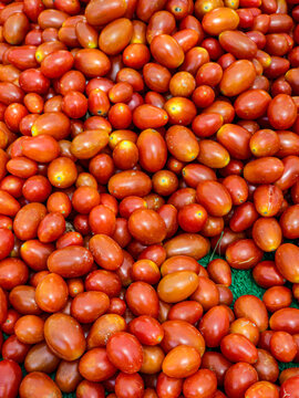 Fresh ripe plum tomatoes on display at a vegetable market captured from a top view showing the abundance of produce