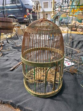 Xalo, Spain - June 20, 2026.Vintage rusted wire birdcage for sale at outdoor flea market among various antiques and items