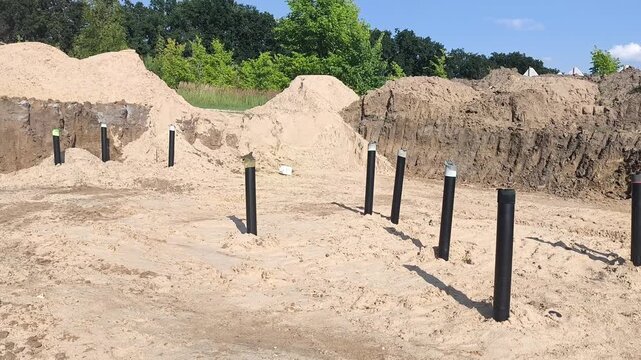 Summer construction site with a large excavation pit, underground utility pipes laid in sand and piles of construction sand. Infrastructure development and engineering works. Horizontal video.