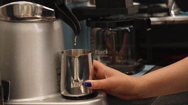 Fresh orange juice is extracted directly into a metal pitcher using a commercial citrus juicer. The preparation highlights fresh ingredients and professional beverage making