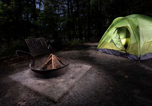 Wood staged and ready for a fire with a dome tent and forest in the background
