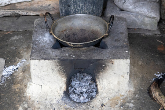Traditional mud stove with cooking pan placed on top in a Banlgadeshi village kitchen. Primitive clay stove used for rural food preparation in countryside outdoors.