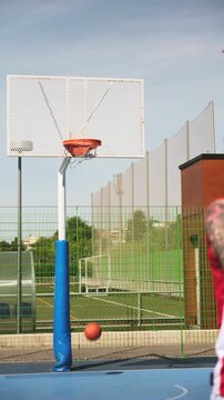 Young man with tattoos shooting a basketball and scoring a basket on a blue court