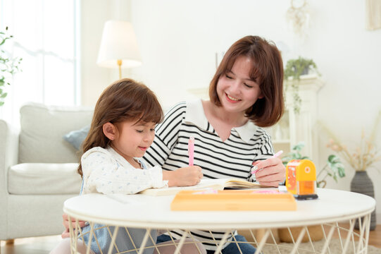 Mom Helps Daughter With Homework in a Bright Living Room on a Sunny Day