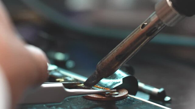 Close-up technician repairing laptop video connector with precision soldering tools