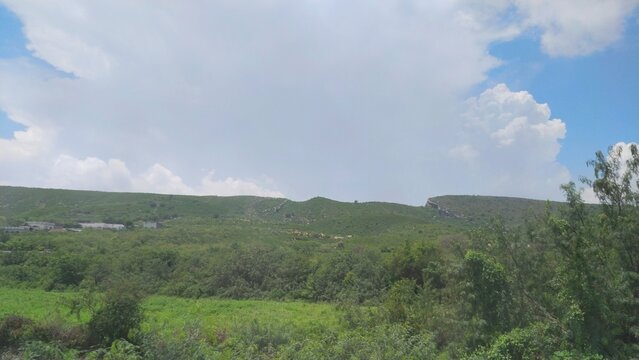Wide View of Rolling Green Hills and Valley Under Clouded Blue Sky