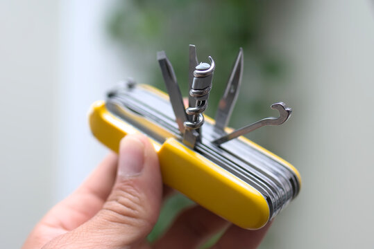 Person holding multipurpose swiss style army knife with yellow handle and open tools with copyspace for text