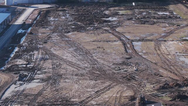 Aerial shot of excavator leveling a muddy construction site