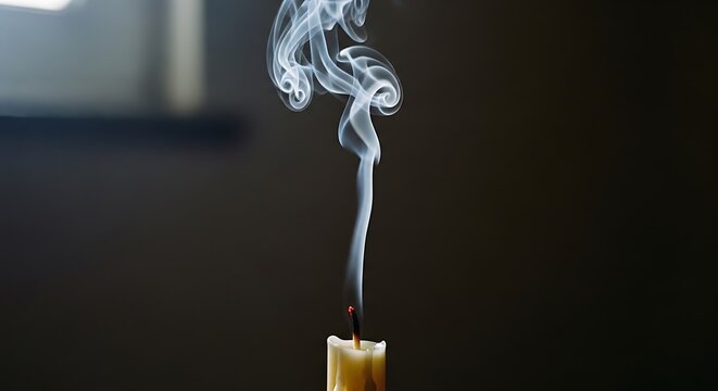 White smoke rising from a freshly extinguished candle against dark background