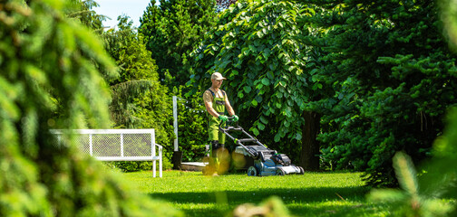 Gardener mows lawn in peaceful backyard on a sunny day © Tomasz Zajda