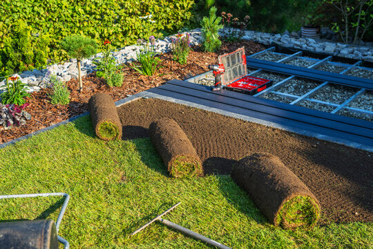Laying sod in a garden area during the afternoon