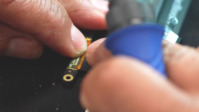 Close-up of technician repairing laptop video connector with precision soldering tools