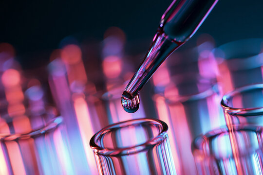 Close Up of Pipette Dispensing Liquid into Laboratory Test Tube with Neon Lighting