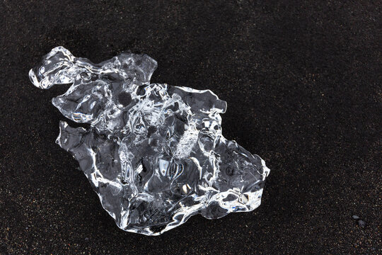 Transparent glacial ice block on black sand at Jokulsarlon Diamond Beach, Iceland