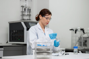Fototapeta premium Expert female scientist mixing chemical solution in beaker with stirring rod at modern laboratory for pharmaceutical formulation, advanced medical research, and commercial biotechnology development.