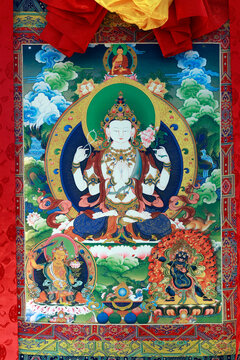 Tibetan Buddhism: a large thangka depicting the four-armed Chenrezig, the bodhisattva of compassion, surrounded by Amitabha, Manjusri, and the dharmapala Mahakala.