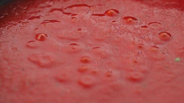 Close up of tomato sauce simmering with bubbles across the surface in pan. Homemade cooking process for pasta sauce or other savory dishes