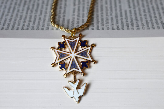 A Protestant Huguenot cross pendant in blue enamel resting on an open Bible.