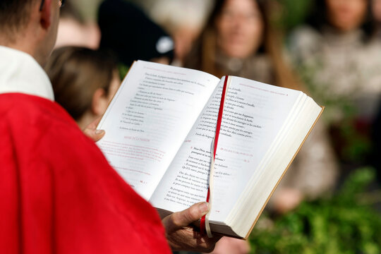 Saint-Jacques Collegiate Church.  A parishioner reads from the Gospel of Matthew during the Palm Sunday procession of Holy Week.