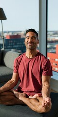 Fototapeta premium Man practicing seated meditation in a bright city apartment by the window for wellness background and mindfulness poster