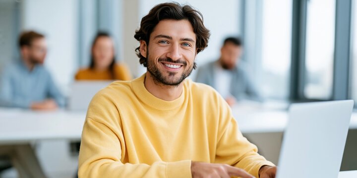 Smiling young man in yellow sweater at classroom laptop for education website background and student profile banner and e learning promotional use
