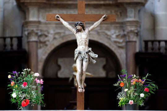 Notre-Dame Collegiate Church. Christ on the Cross, a polychrome wooden statue, surrounded by bouquets of flowers.