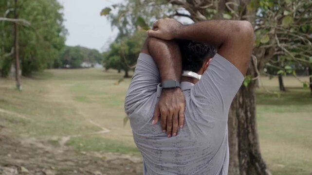 Athletic male stretching arms before running outdoors