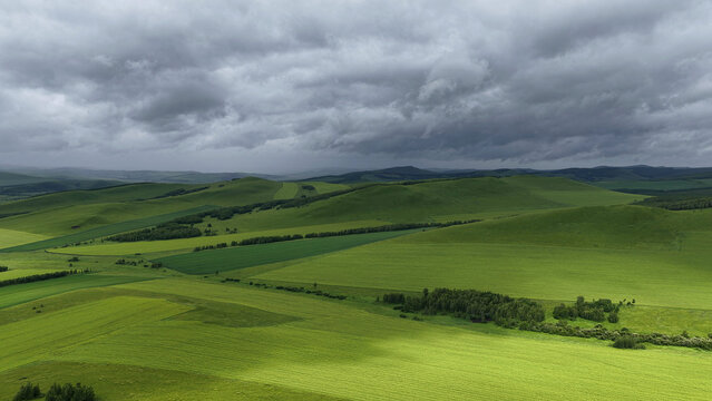Aerial view of rolling farmland under dramatic clouds in Hulunbuir, Inner Mongolia