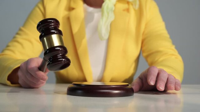 Auctioneer in yellow jacket with gavel in hand conducts auction, recording final bidding on lot close-up